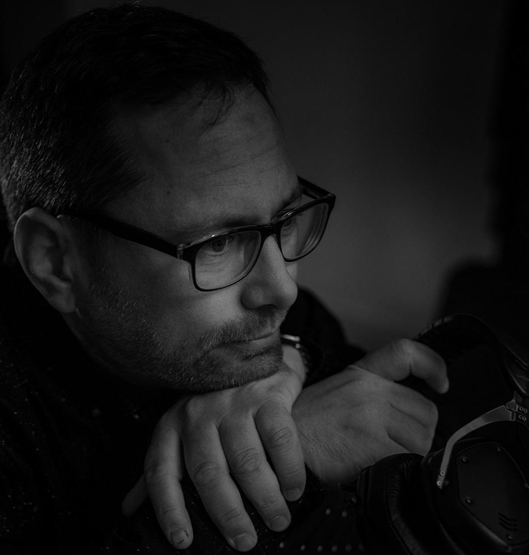 DJ Hope Abeacan, black and white contemplative portrait, resting chin on headphones, thoughtful gaze